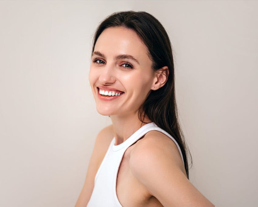 woman with long dark hair and clear skin smiling