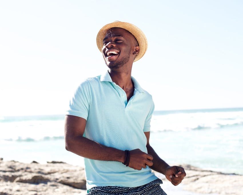 man wearing a blue shirt and straw hat at the beach
