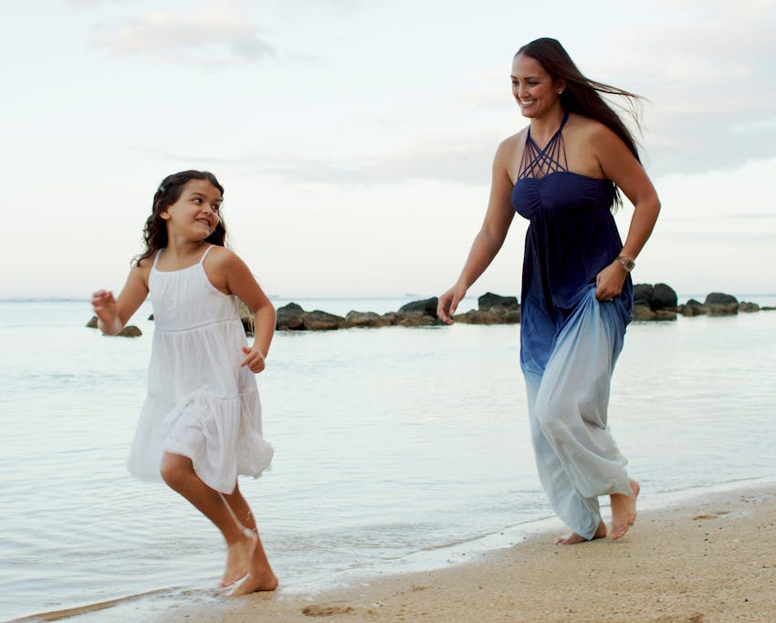 mother and daughter running and smiling at the beach