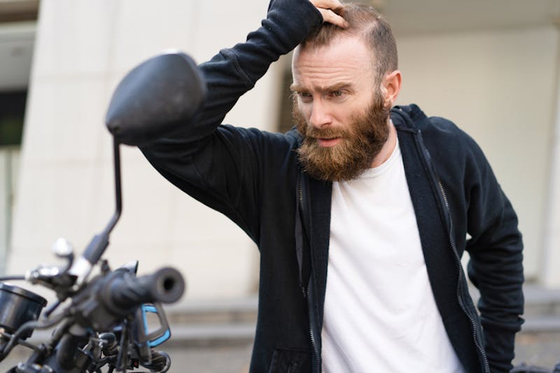 A stressed man next to his motorcycle