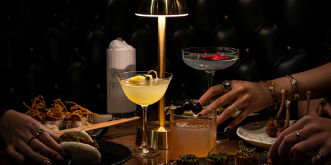 Table in the dark with lamp, food and cocktails