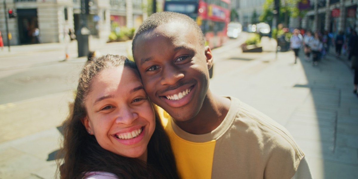 Man and woman smiling at the camera with highstreet behind