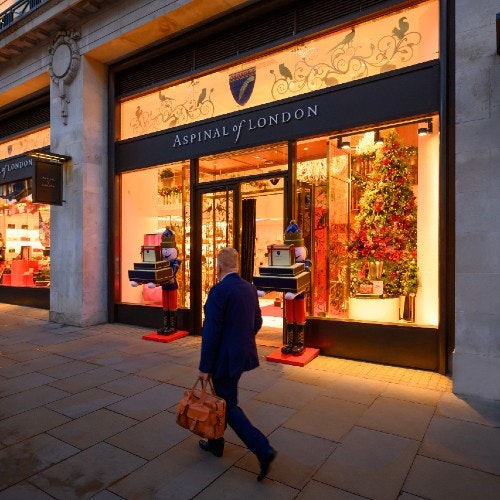 Man walking past a shop that is lite up at night