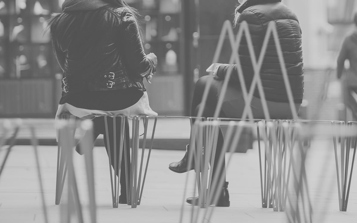 Black and white photo of backs on people on benches