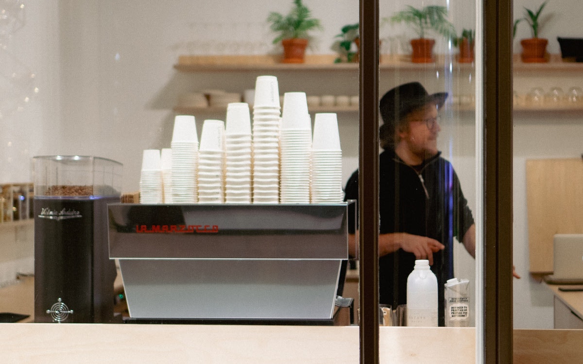Man behind  coffee machine with takeaway cups