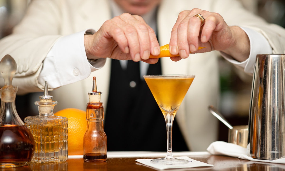Hands squeezing fruit into cocktail glass