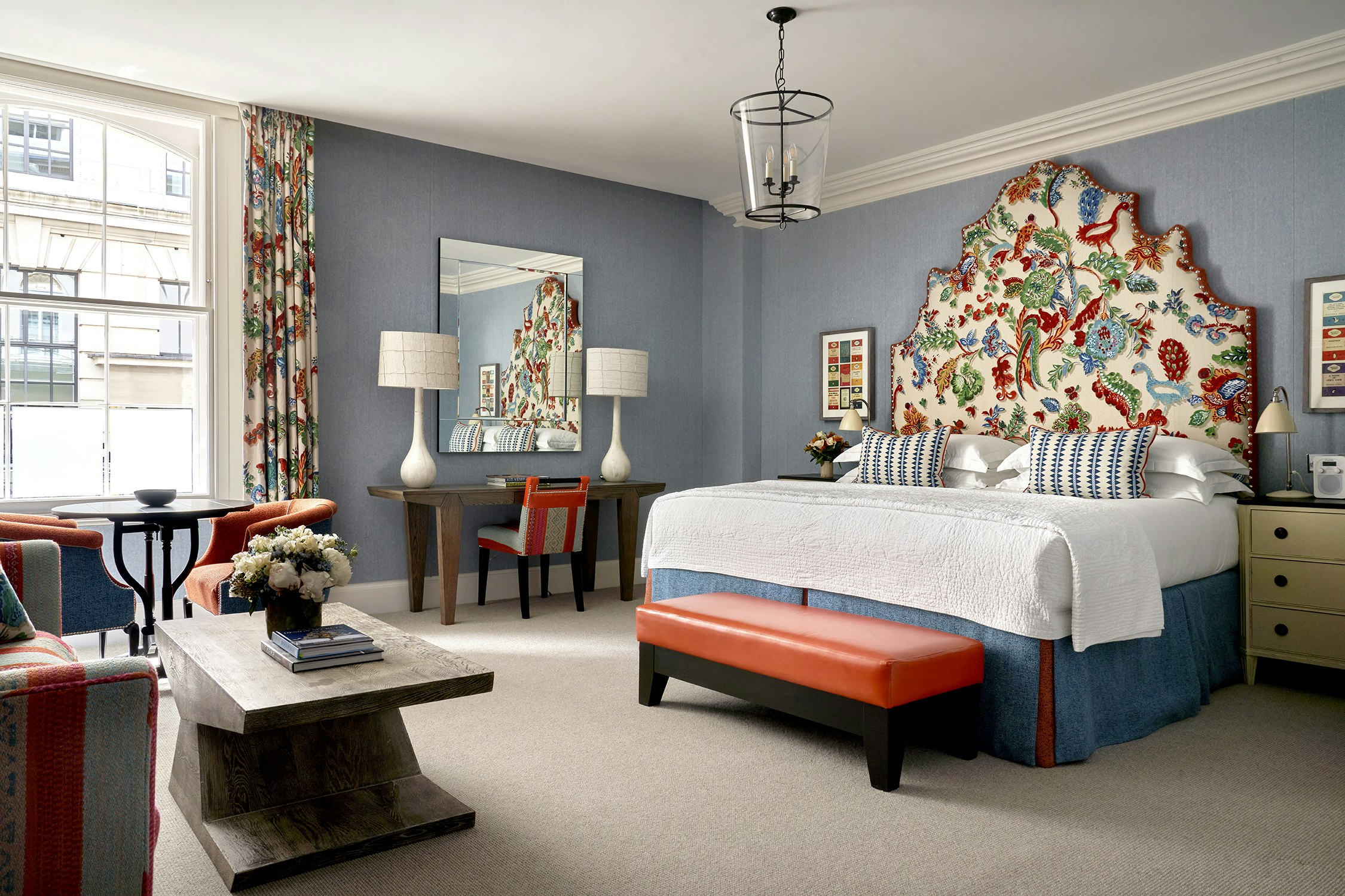 Bedroom with red bench, table with flowers and floral patterns