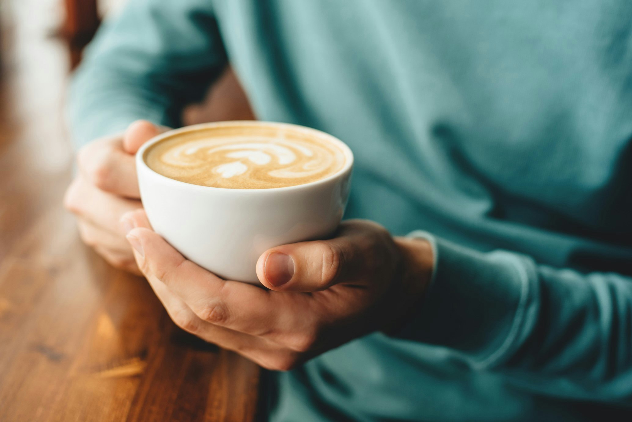 Hands holding a white cup of coffee
