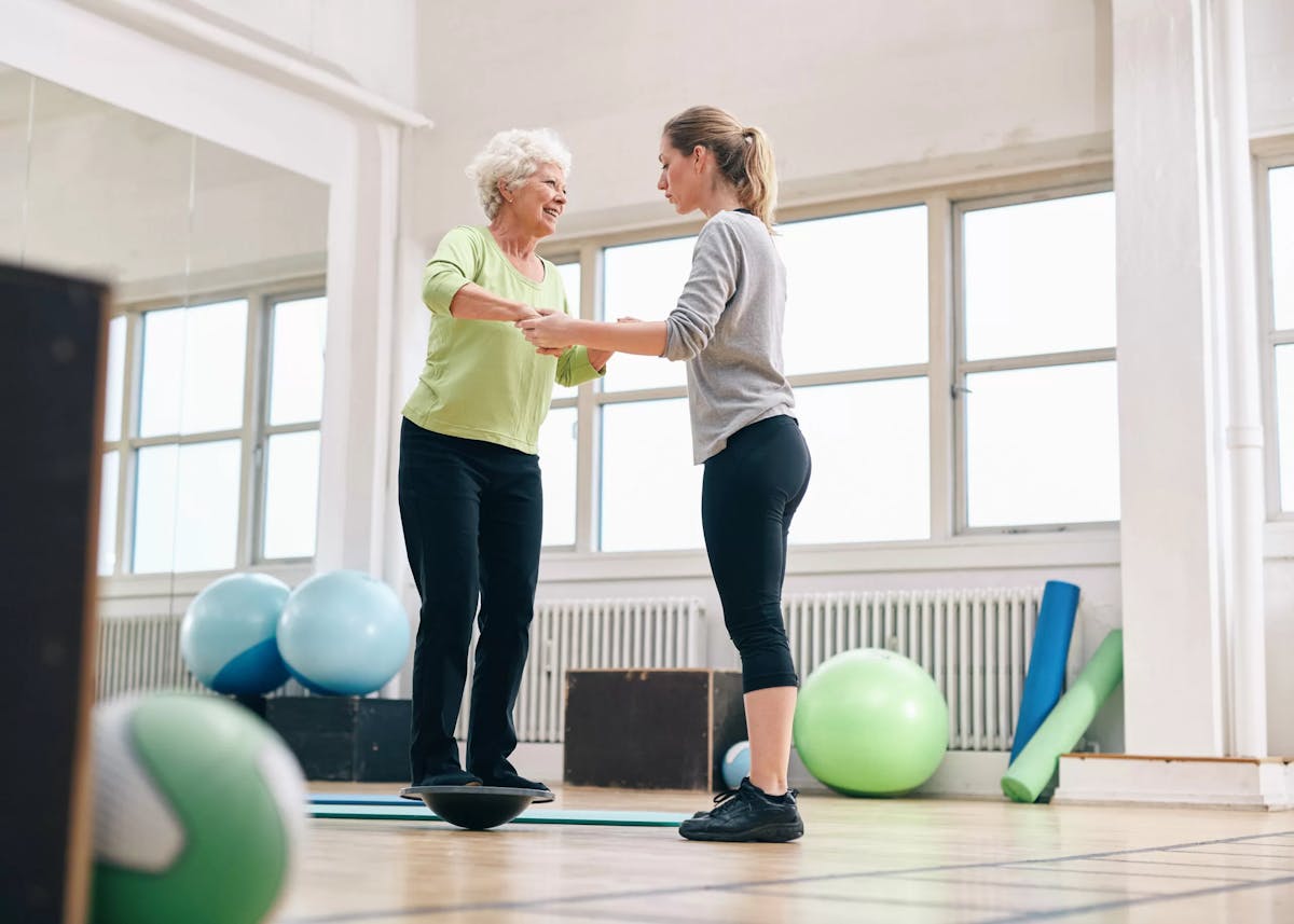 Therapist assisting older adult with balance exercise
