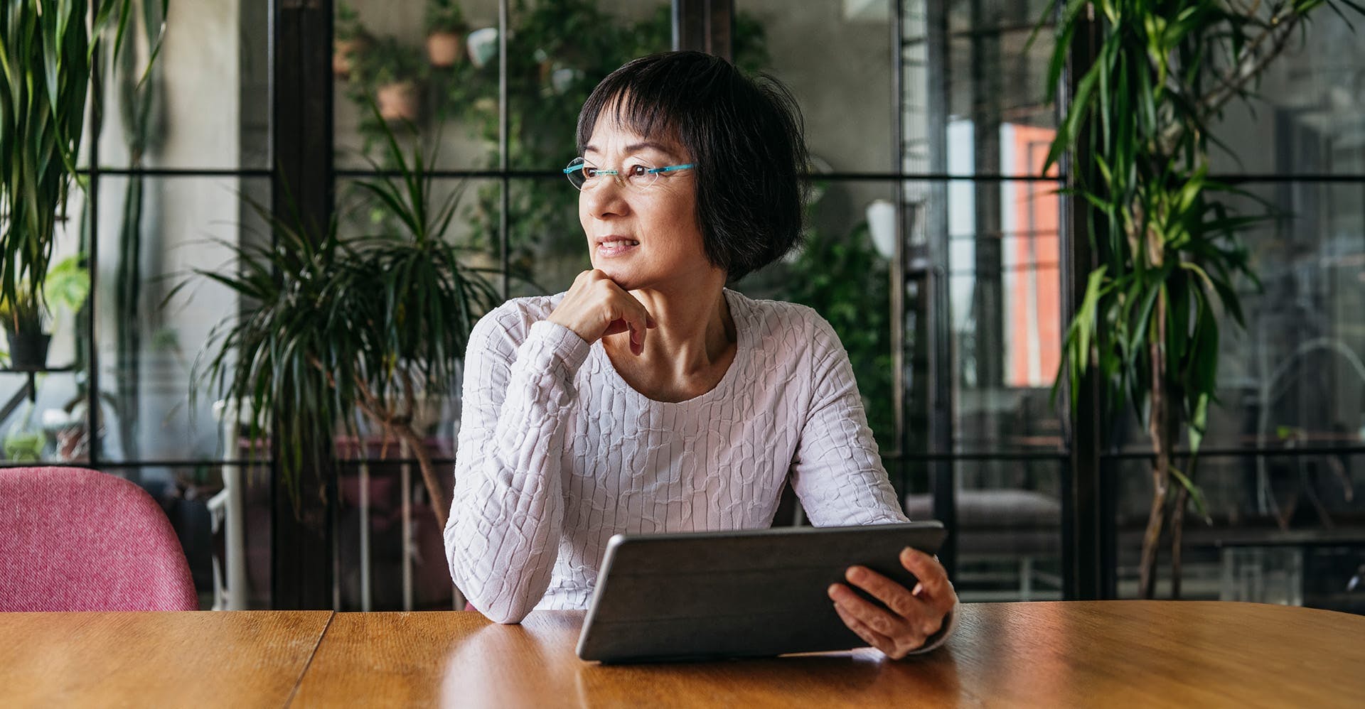 older woman sitting at a table on a tablet