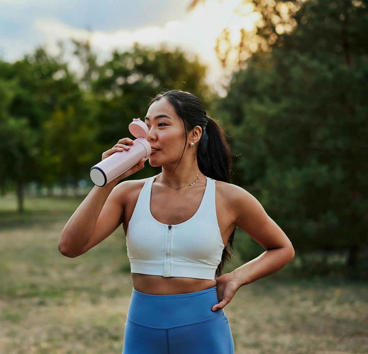woman in workout gear drinking out of a water bottle