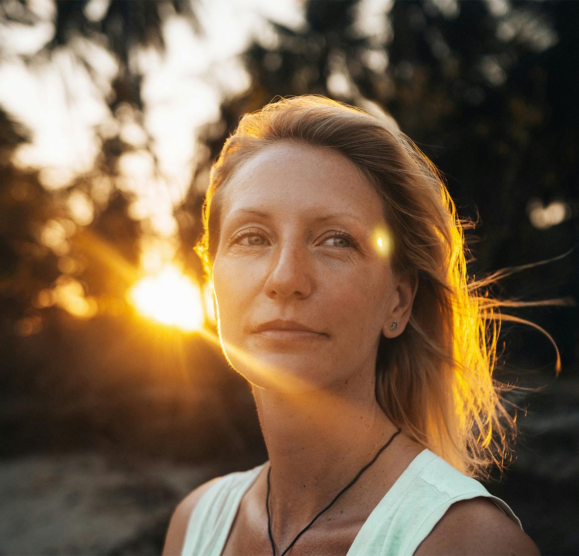 woman outside with the sun shining behind her