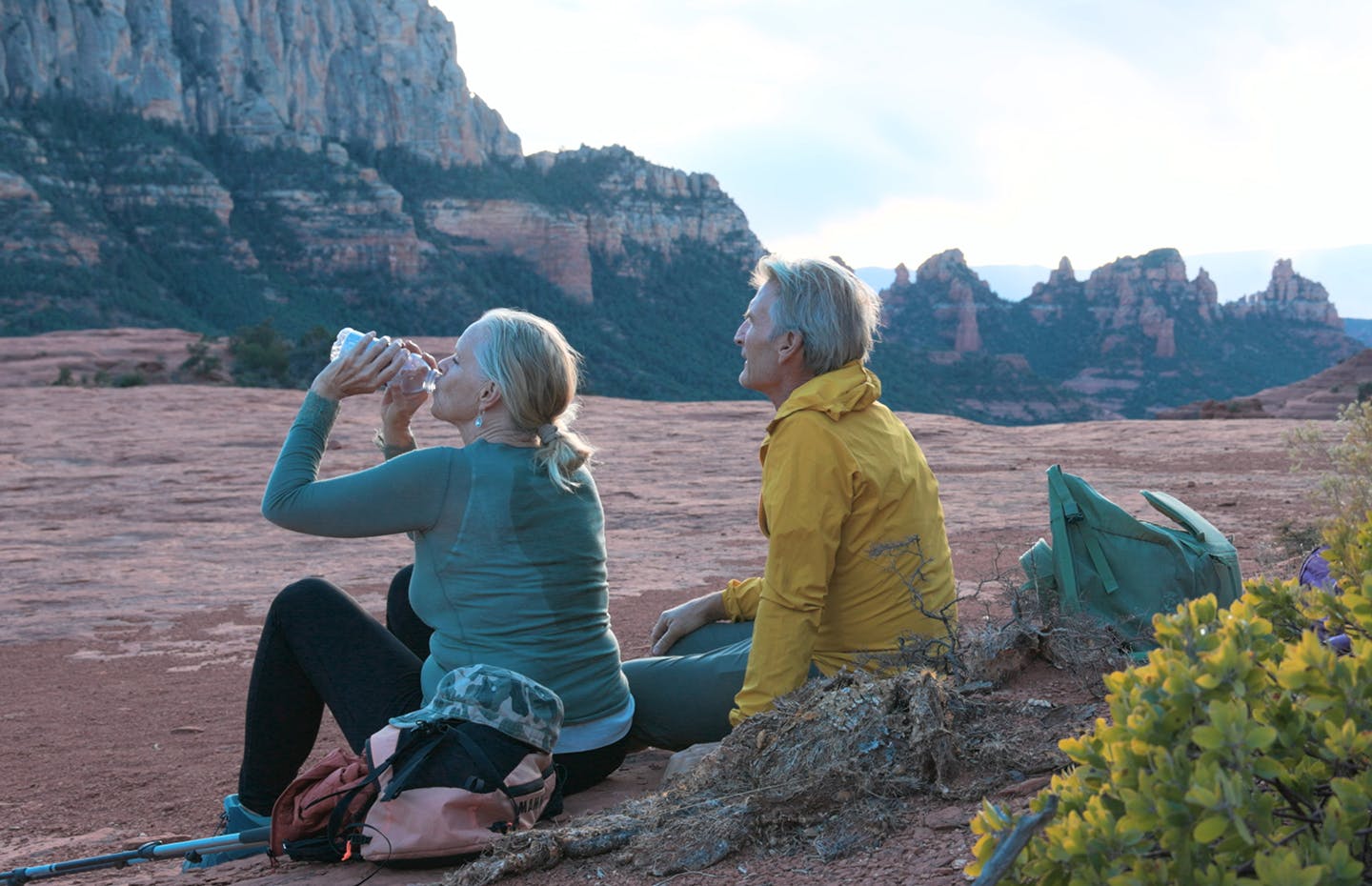 older couple sitting outside drinking water while on a hike