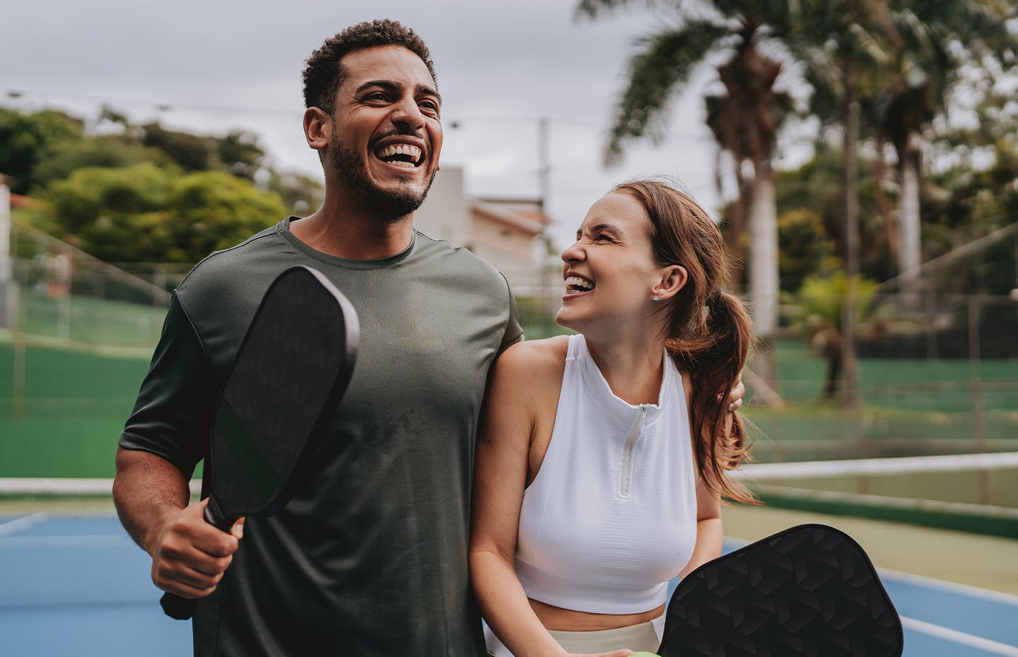 young couple smiling while playing pickleball