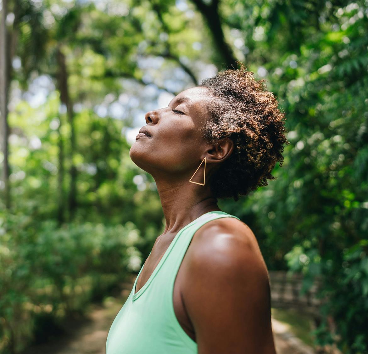 woman outside in forest with her head tilted upwards
