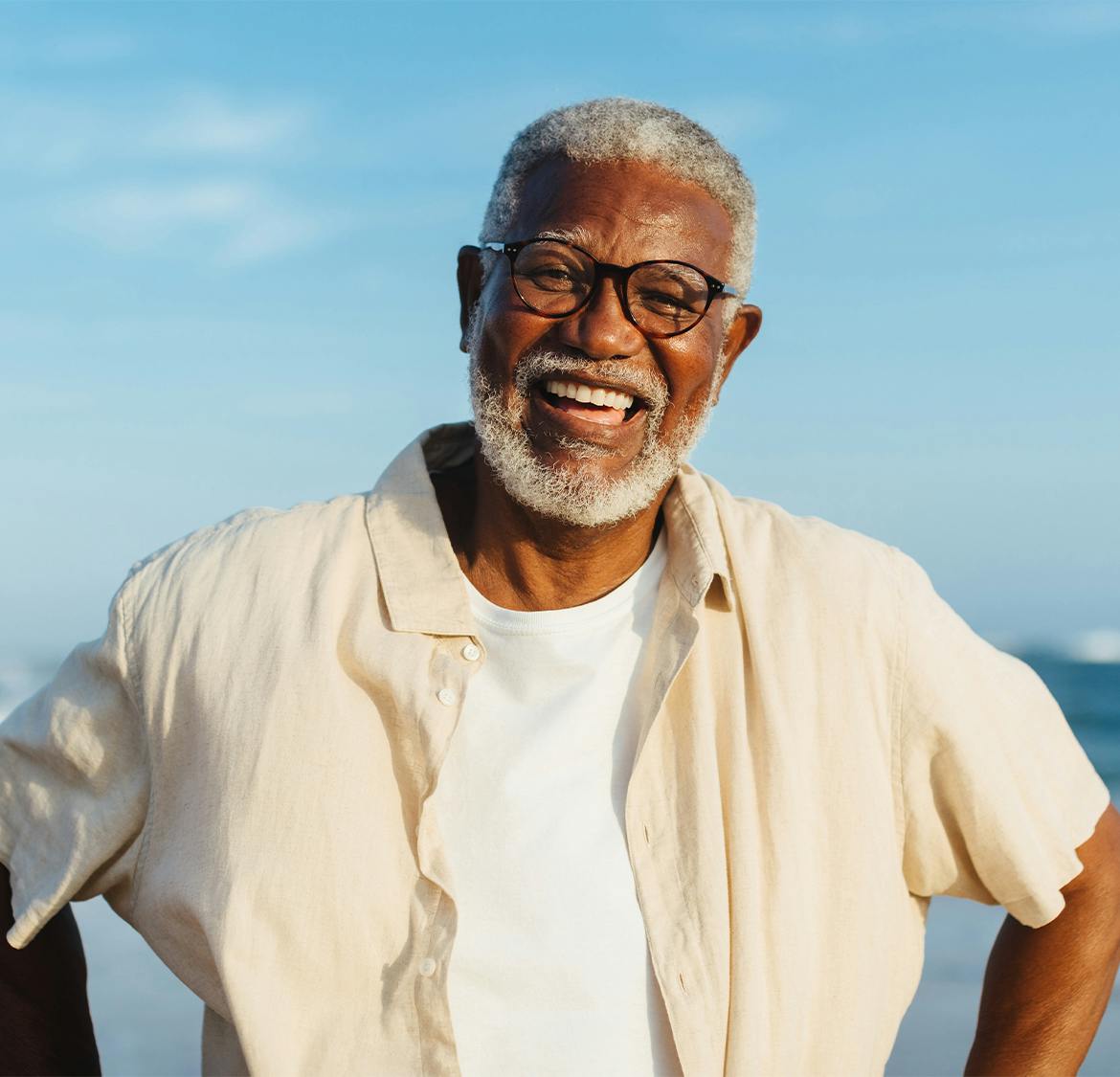 older man with flowy buttoned shirt smiling