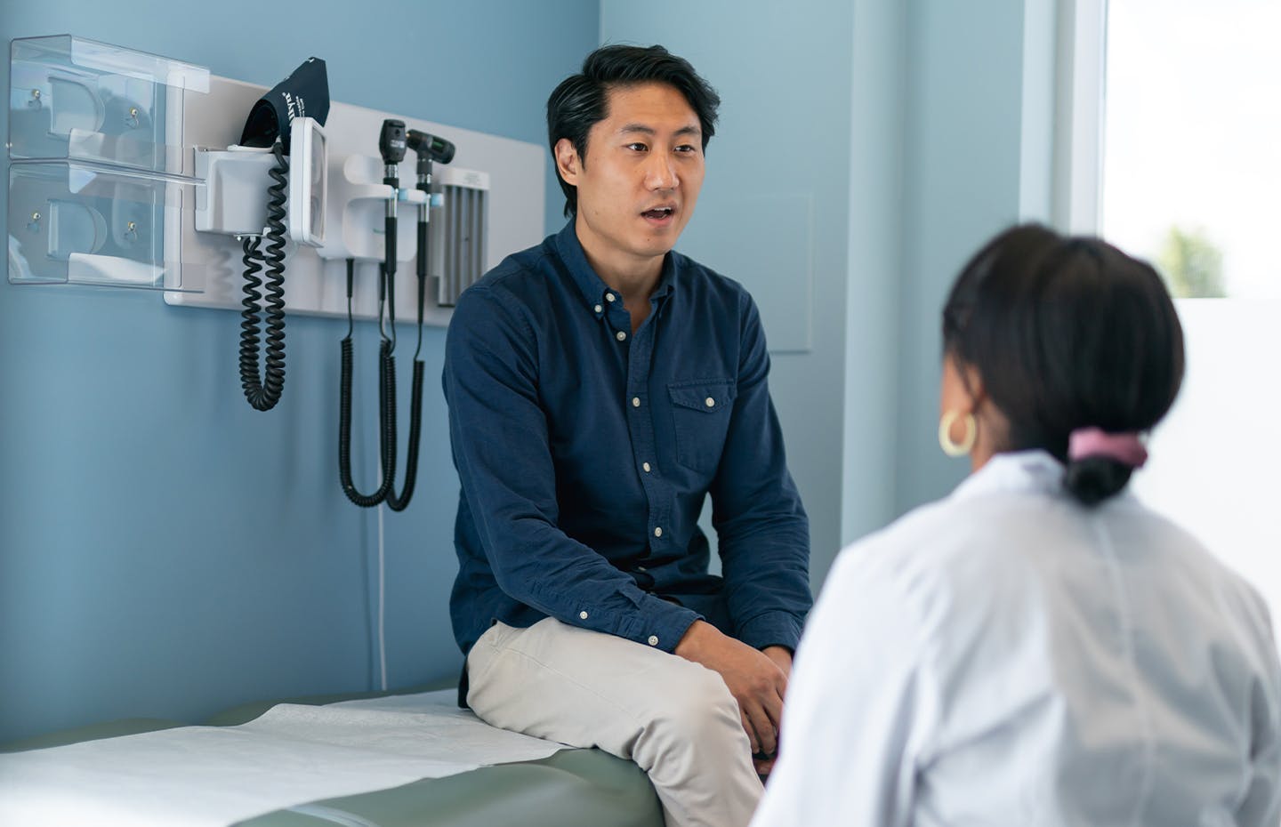 man sitting on exam chair with doctor in front of him