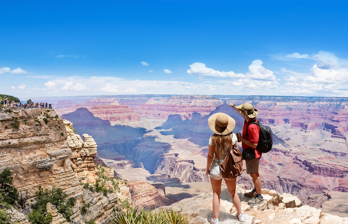 couple wearing hats and pointing out to the mountain scape