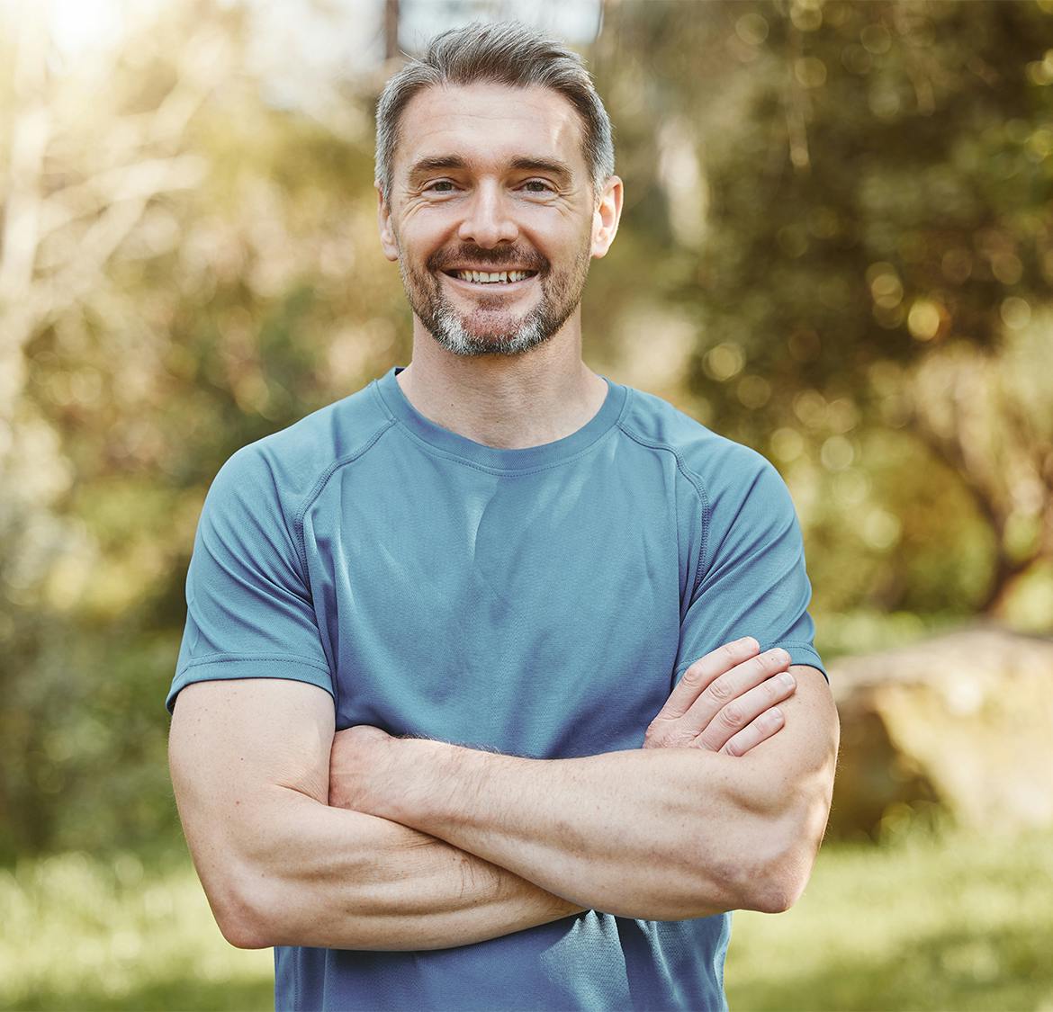 man in blue shirt crossing his arms outside