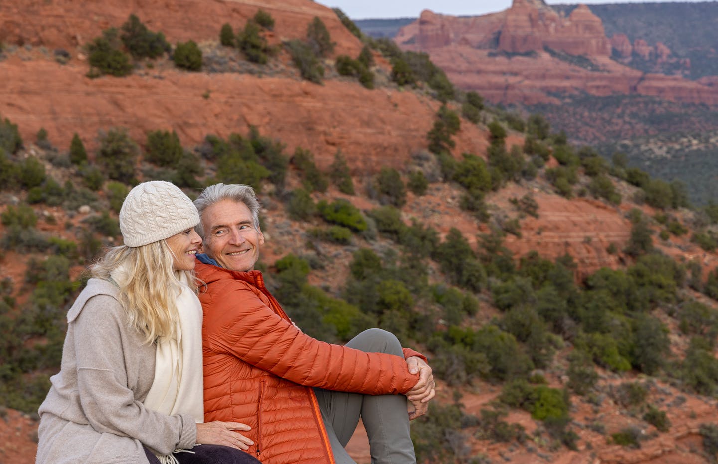 couple sitting on mountain cliff looking at the view