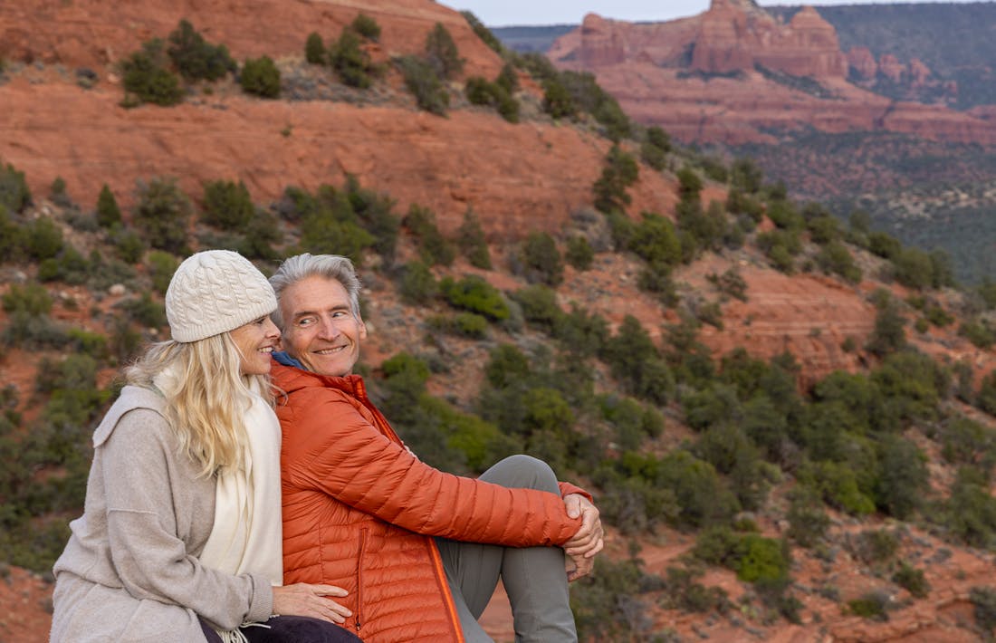 couple sitting on mountain cliff looking at the view