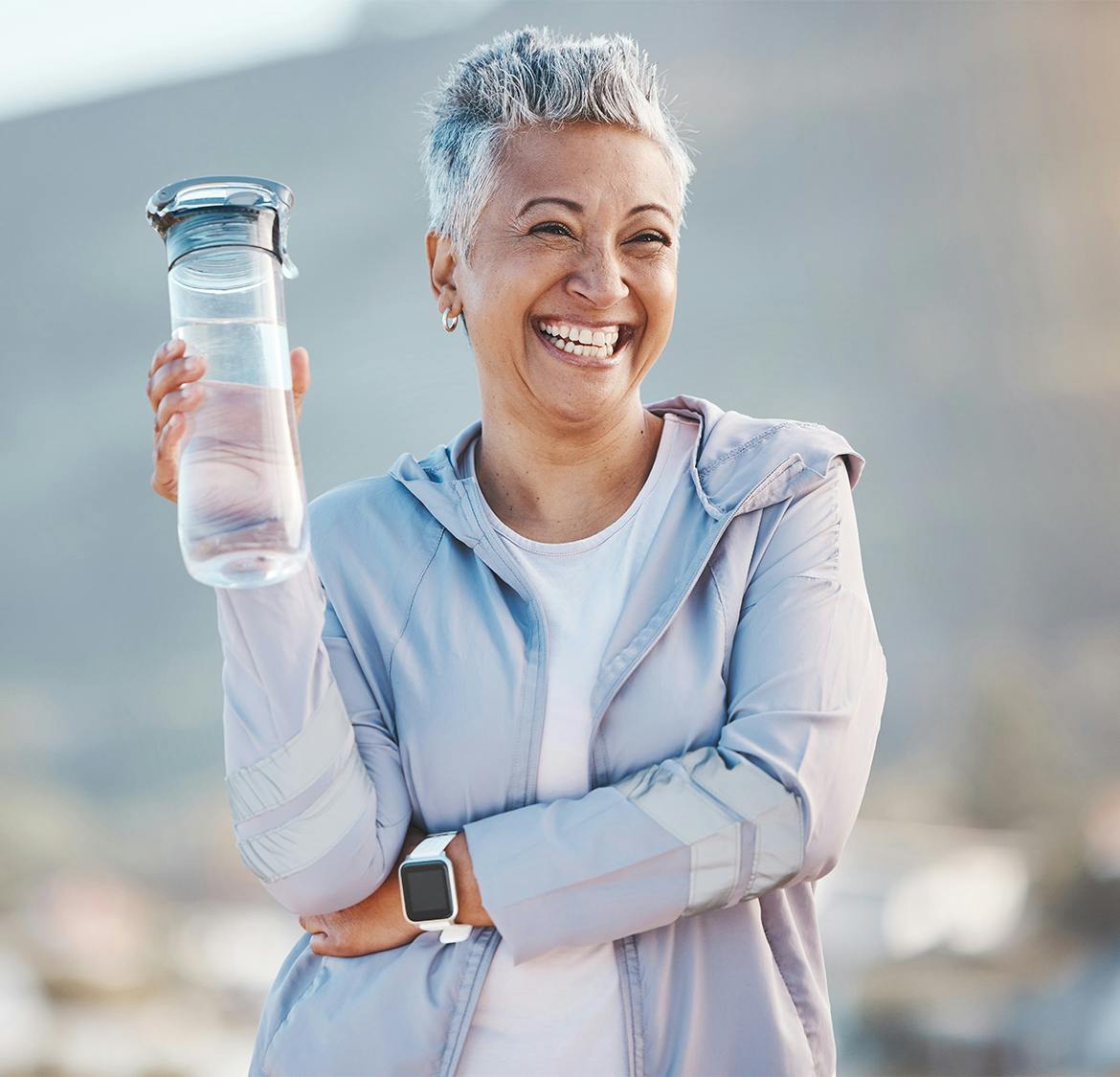 woman smiling and holding up her water bottle