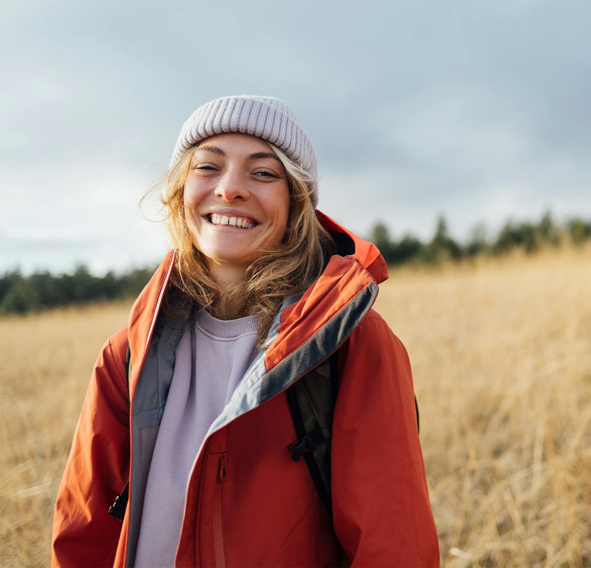 woman in hoodie and jacket outside smiling