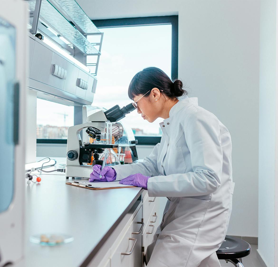 doctor looking through microscope and filling out form