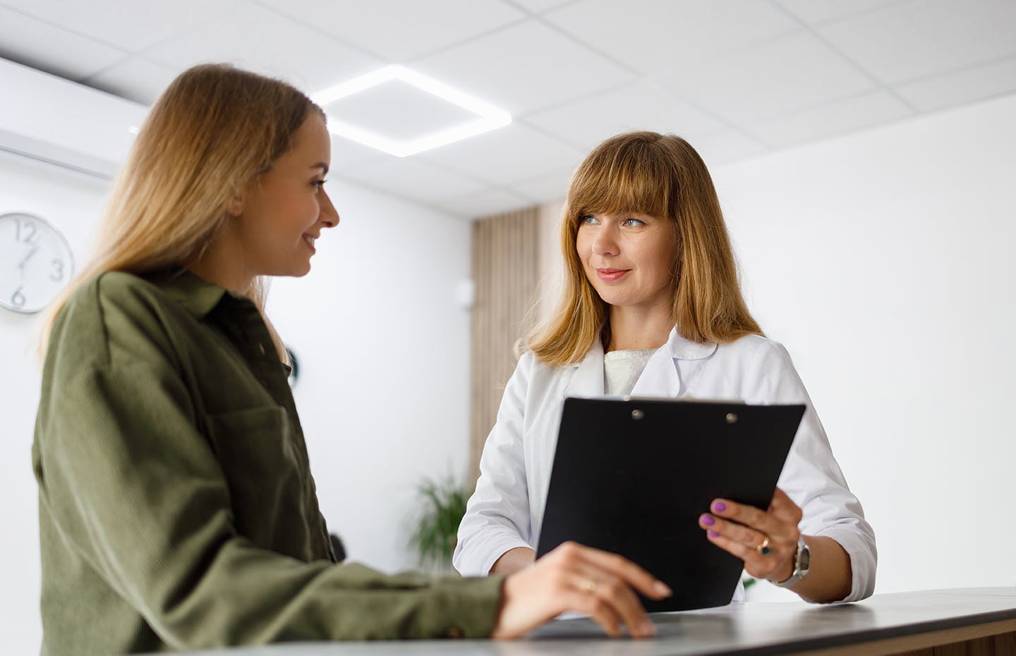 woman holding clip board with patient in front of her
