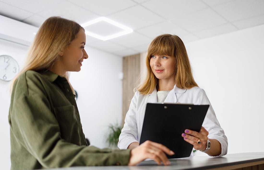 woman holding clip board with patient in front of her