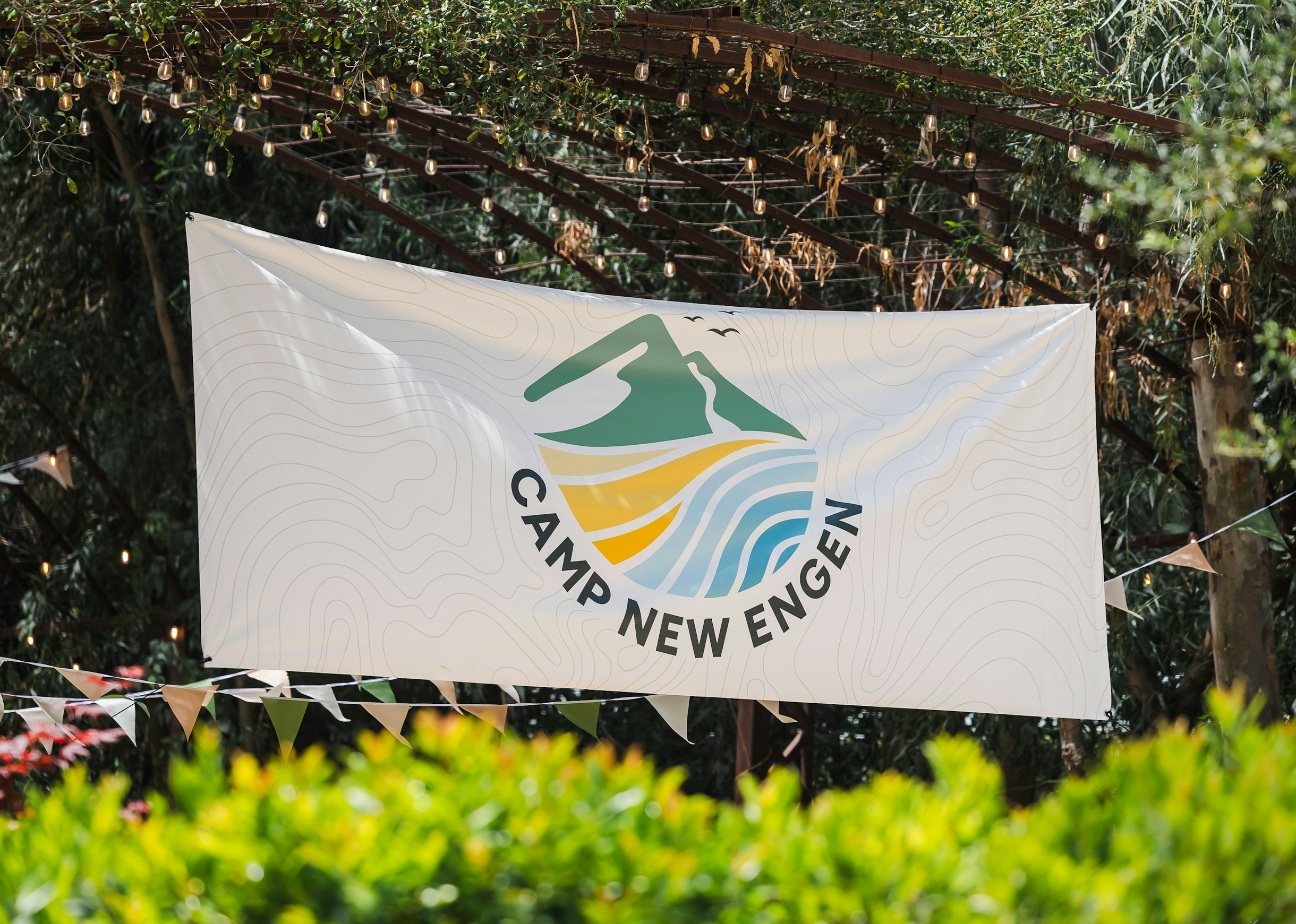 Camp New Engen 2026 Outdoor Event Banner at Calamigos Ranch Camp New Engen 2026 banner hanging under string lights at an outdoor marketing summit at Calamigos Ranch in Malibu.
