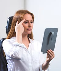 Girl looking in the mirror lifting her eyebrow