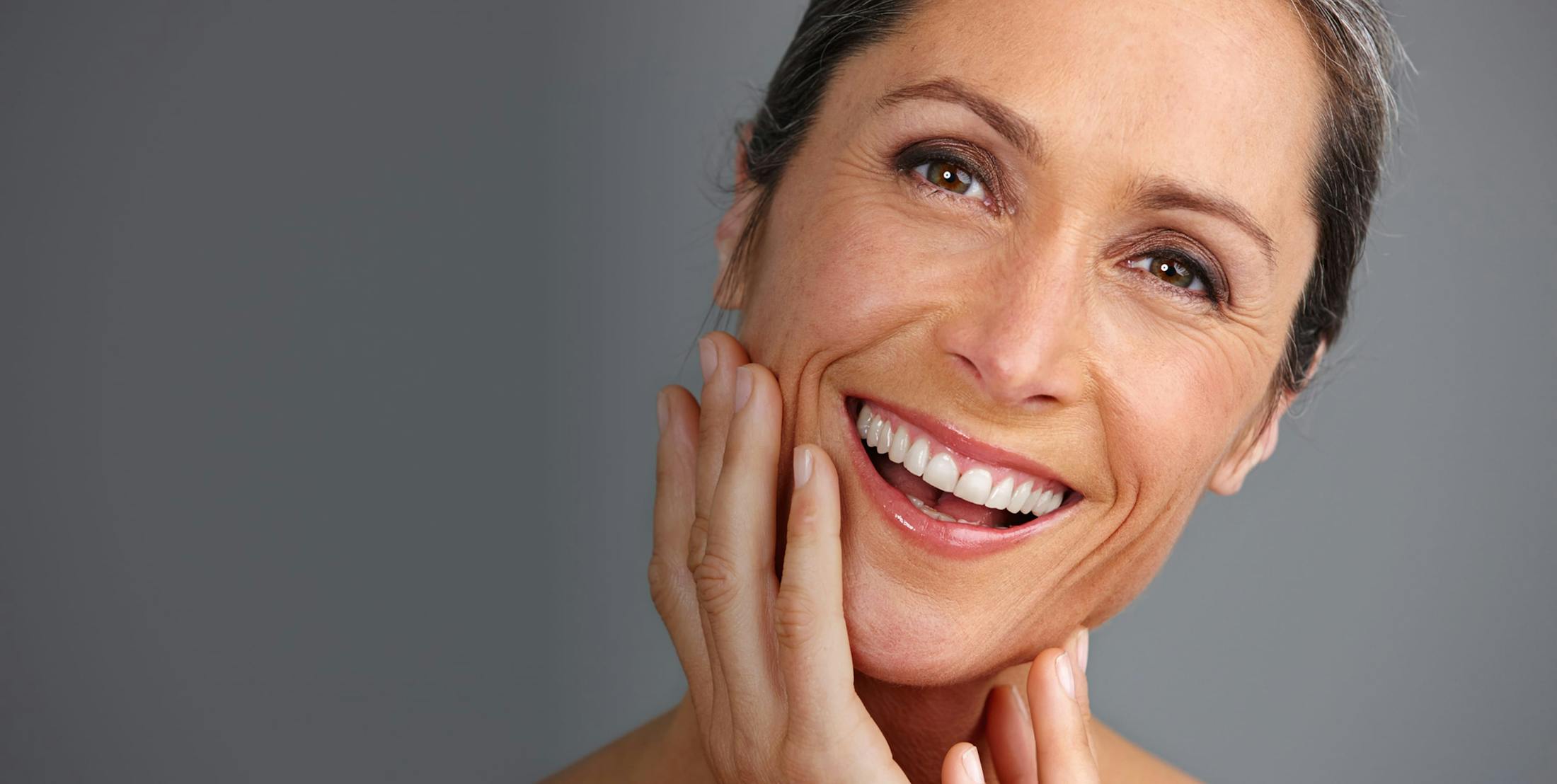 woman smiling and touching her lower face
