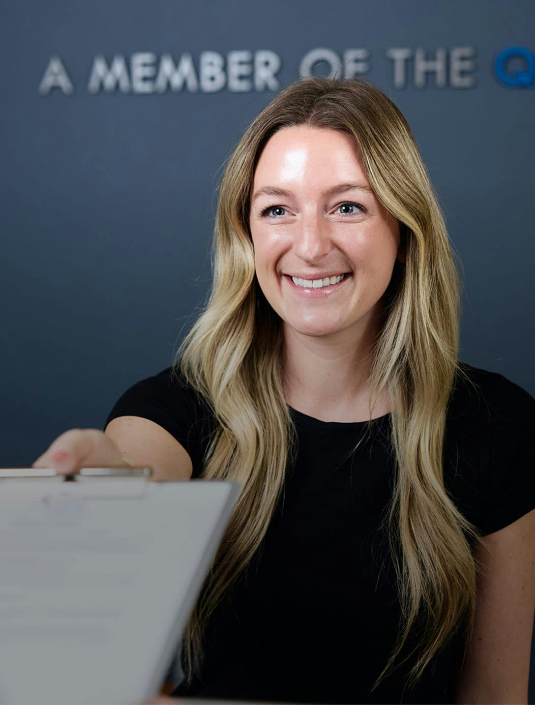 woman smiling handing someone paperwork