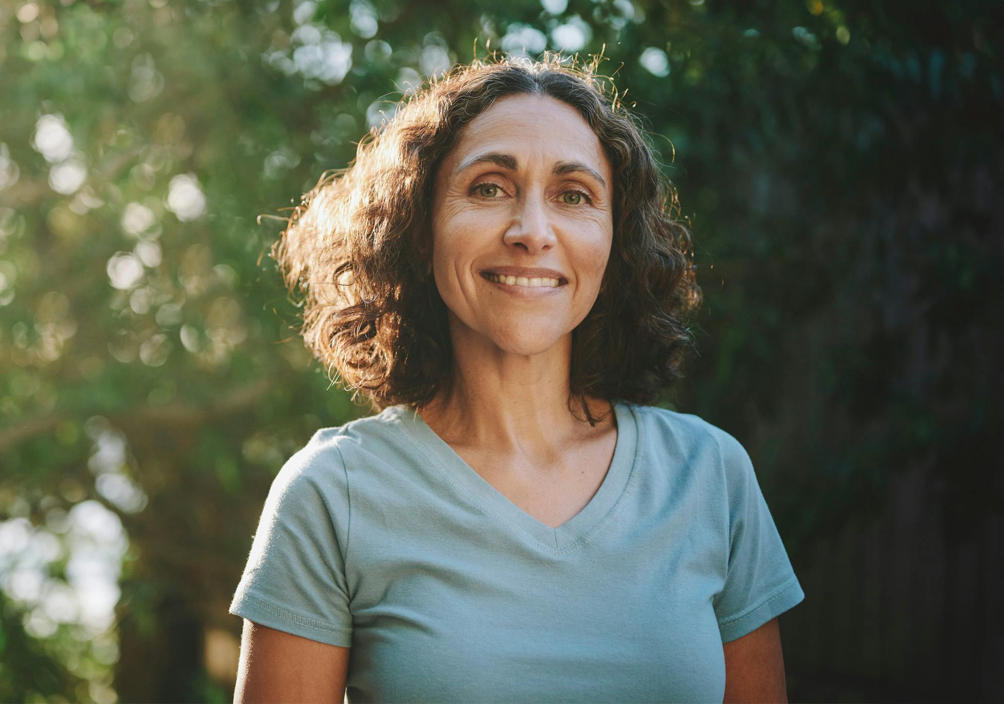 woman with short curly hair in gray shirt outside