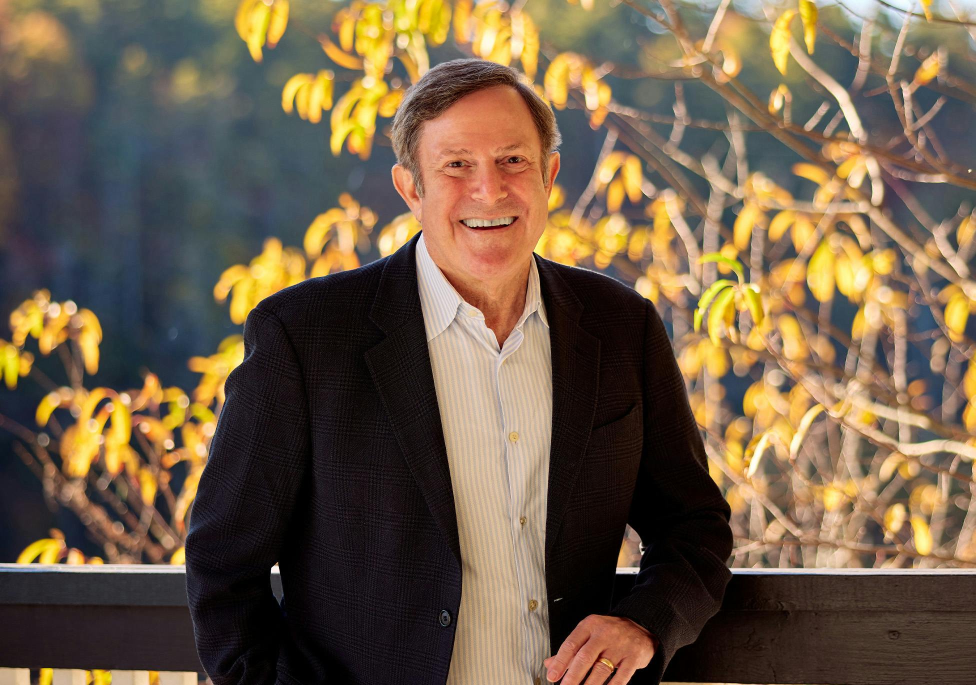 Andrew A. Strauss in black suit jacket with elbow on railing