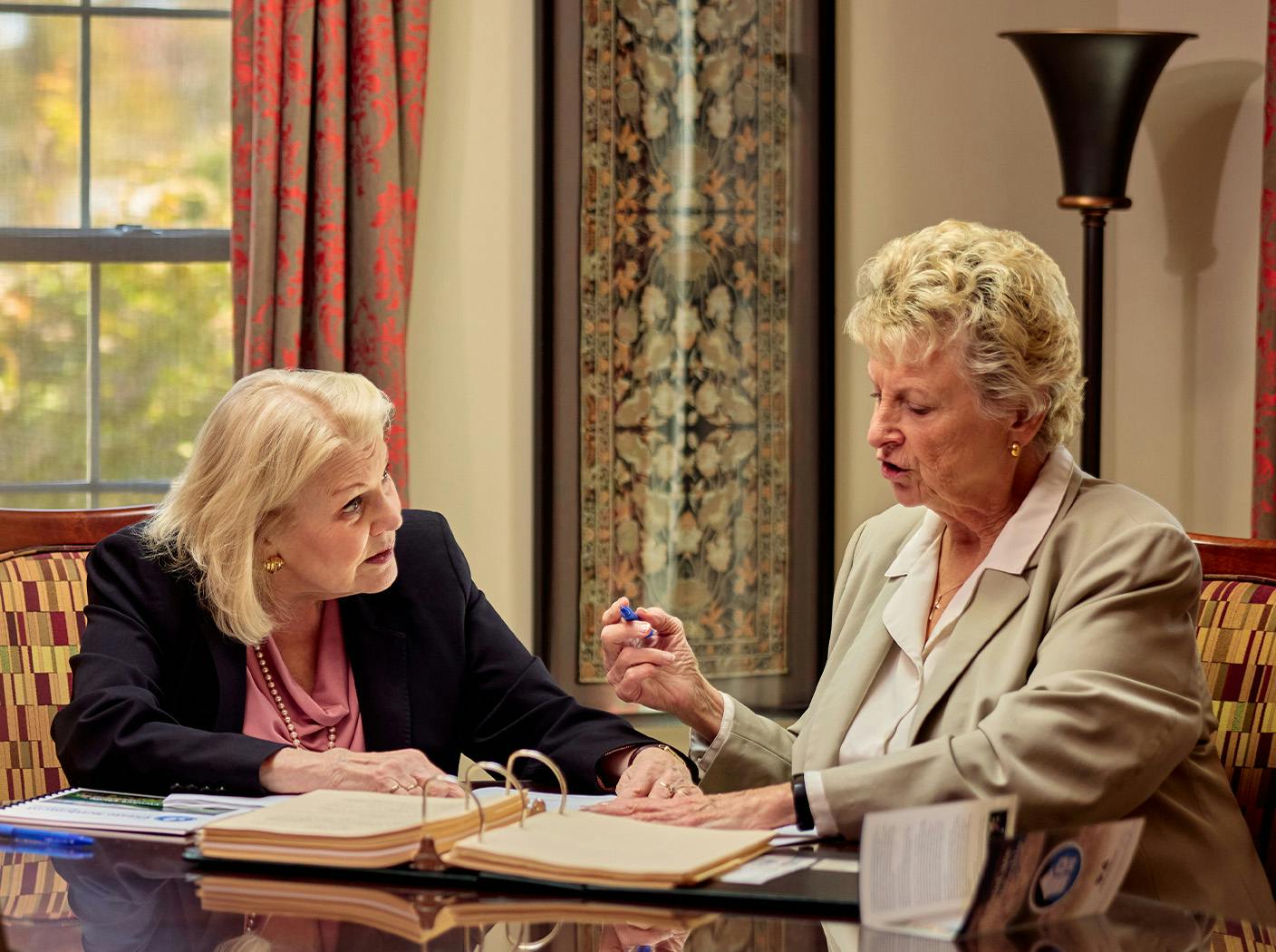 2 ladies in suits looking at paperwork together