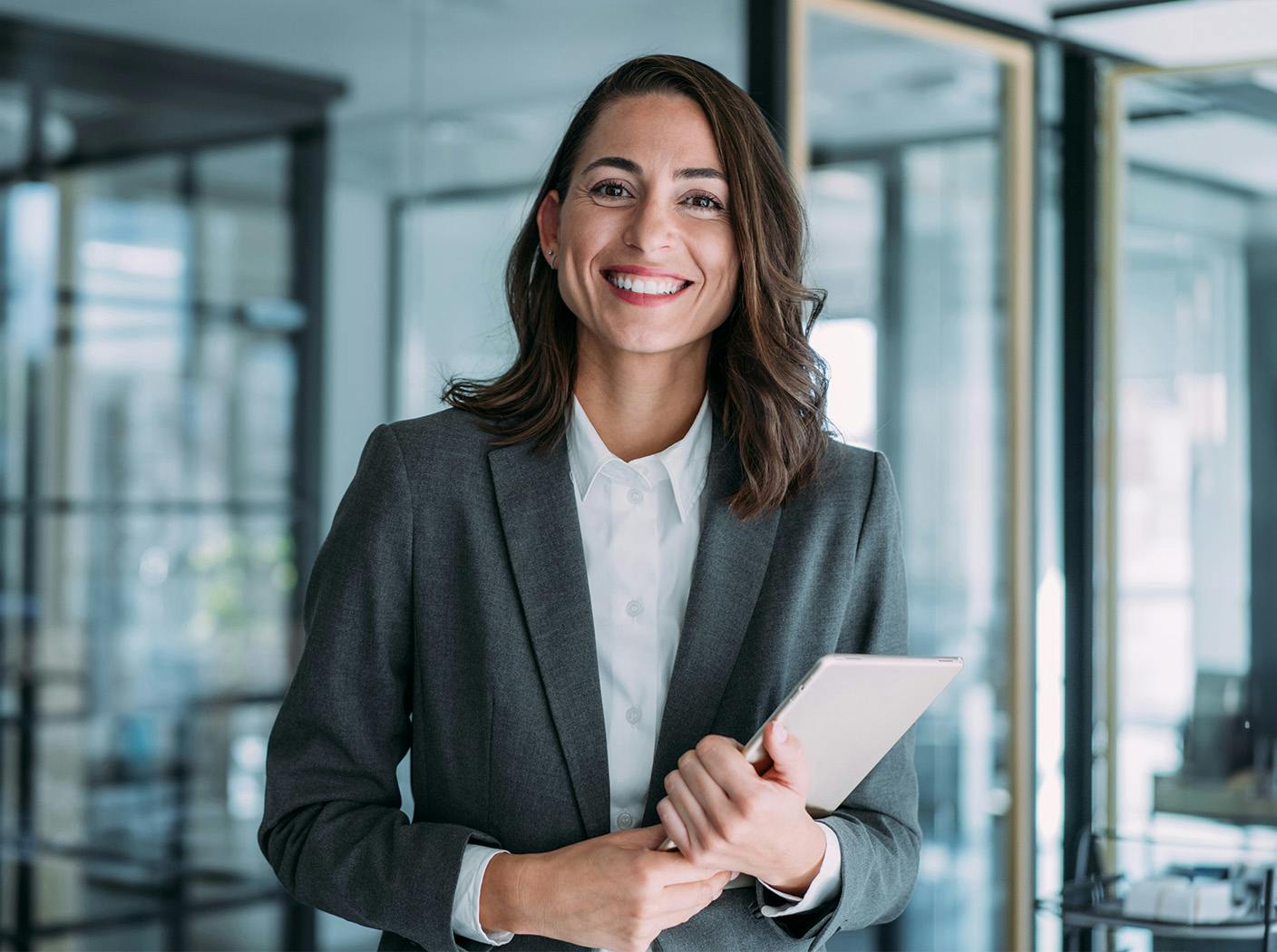 woman in a suit smiling and holding an ipad