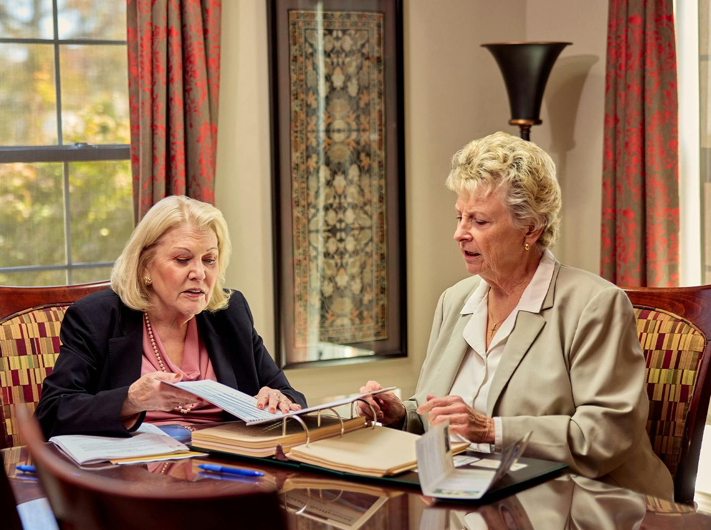2 ladies sitting down and looking at forms together