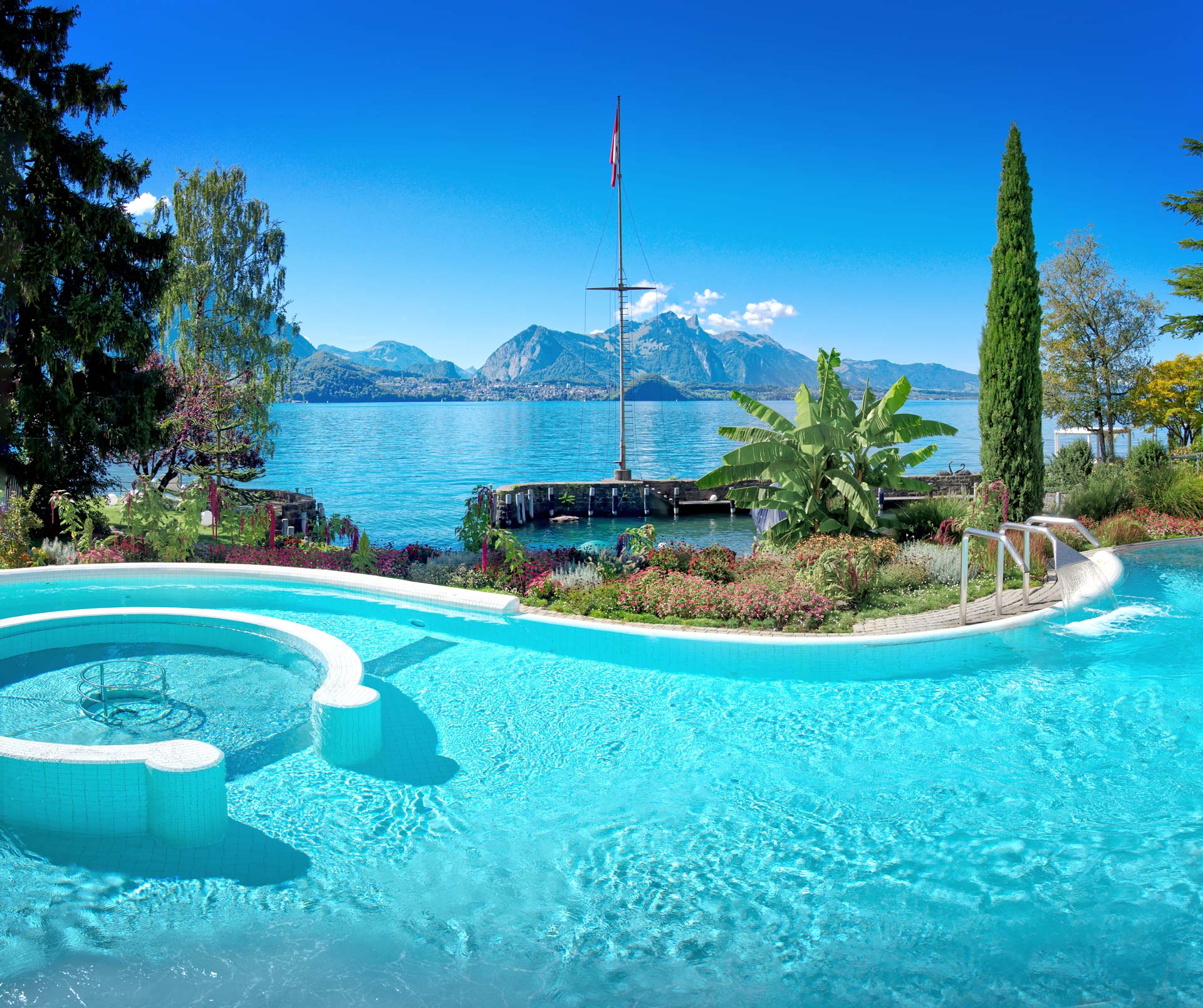 Geschwungenes Schwimmbad , dahinter der Thunersee und die Berge im Sommer