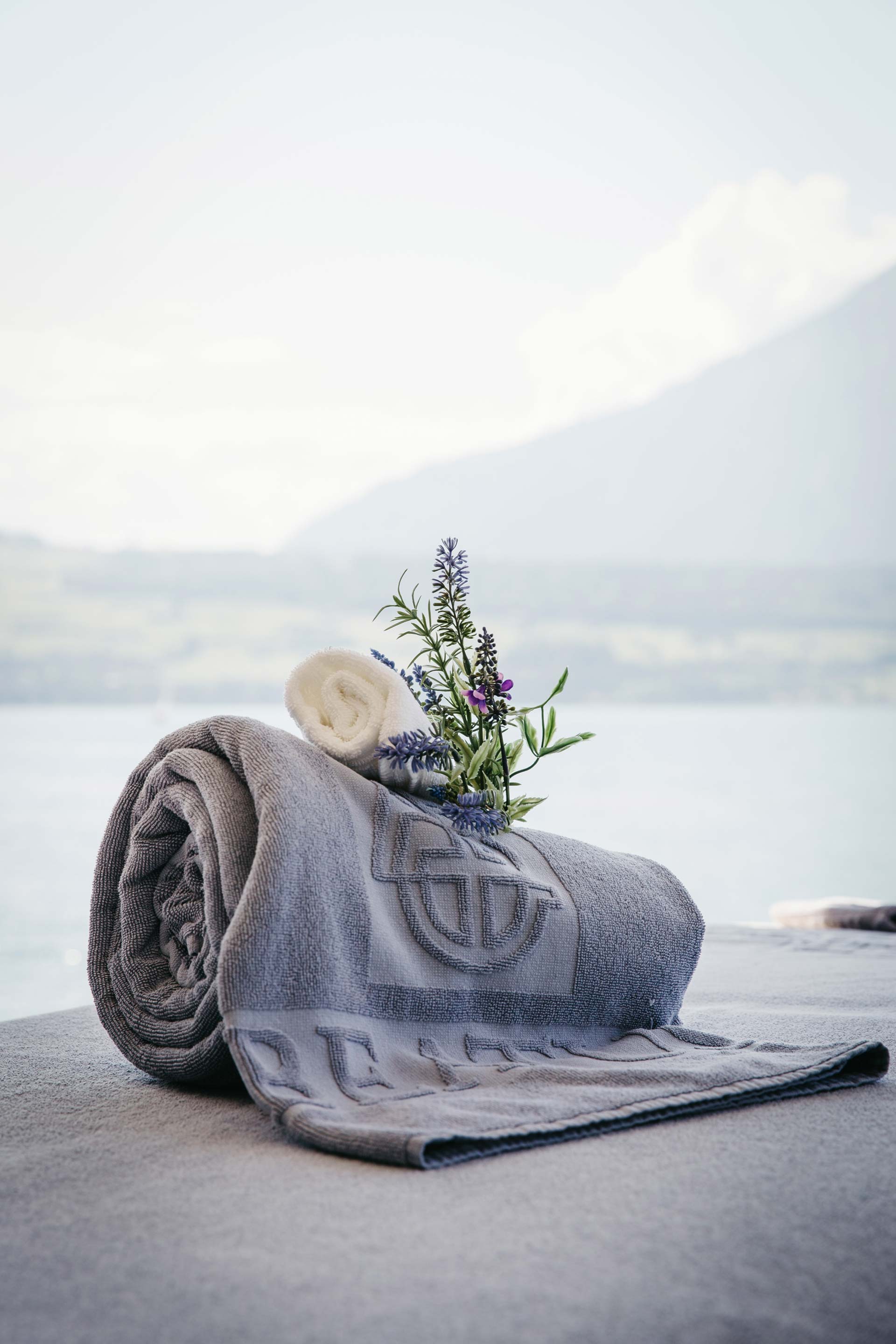 Serviette de bain avec bouquet d'herbes sur la table de massage devant le lac