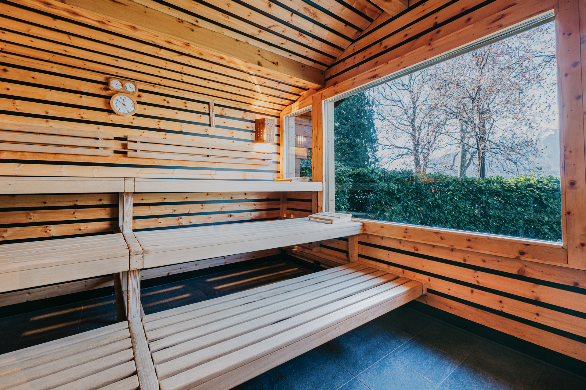 Saunakabine ganz mit Holz ausgekleidet und Steinboden, grosses Fenster Richtung See