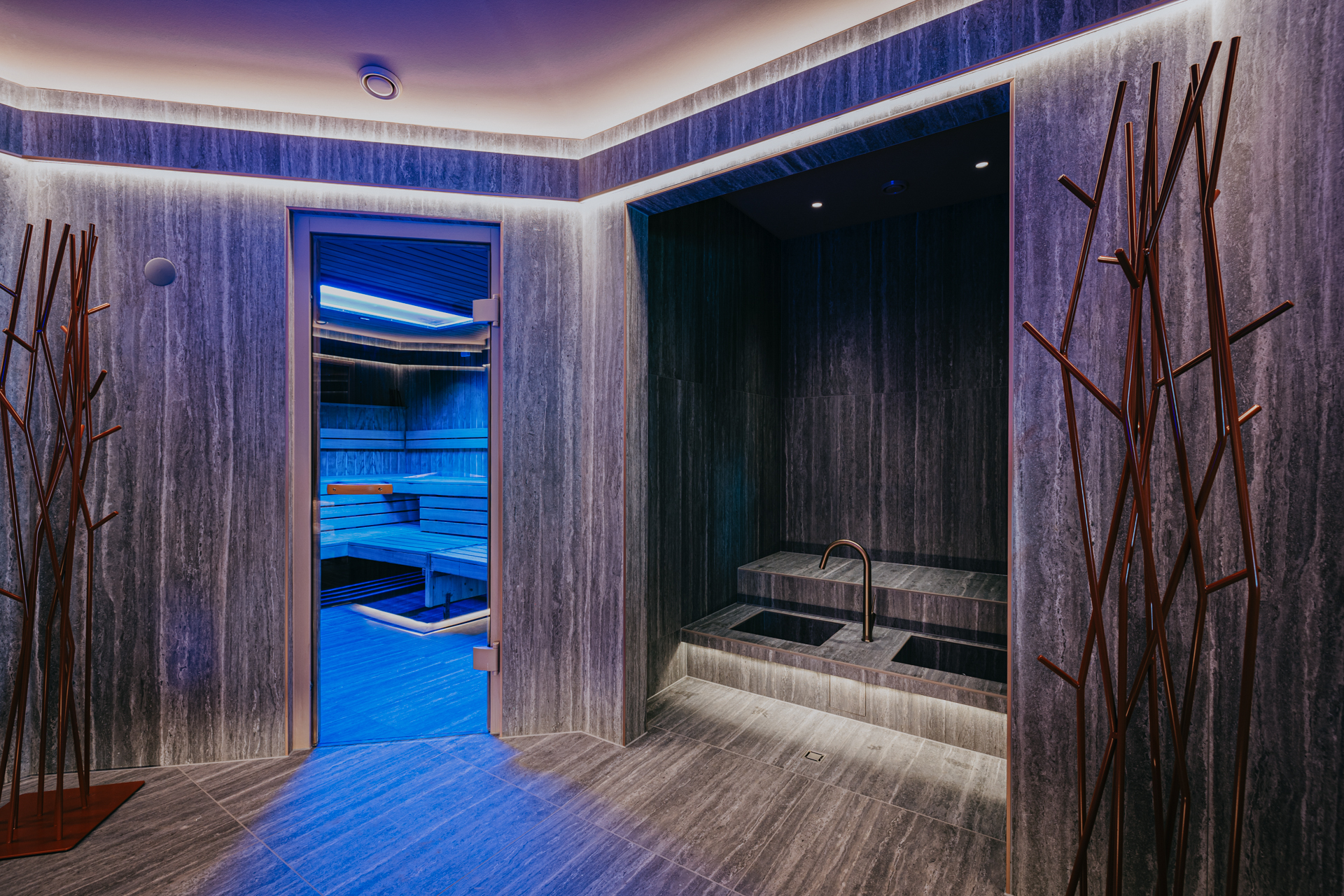 Two pools for a foot bath with tap, view into a blue-lit sauna cabin