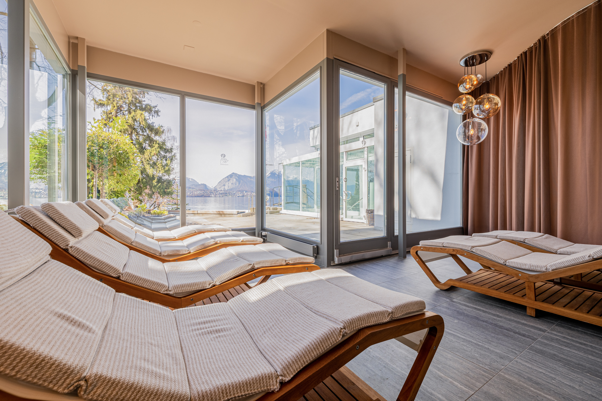 Chaises longues moelleusement rembourrées, derrière une terrasse ensoleillée donnant sur le parc et le lac
