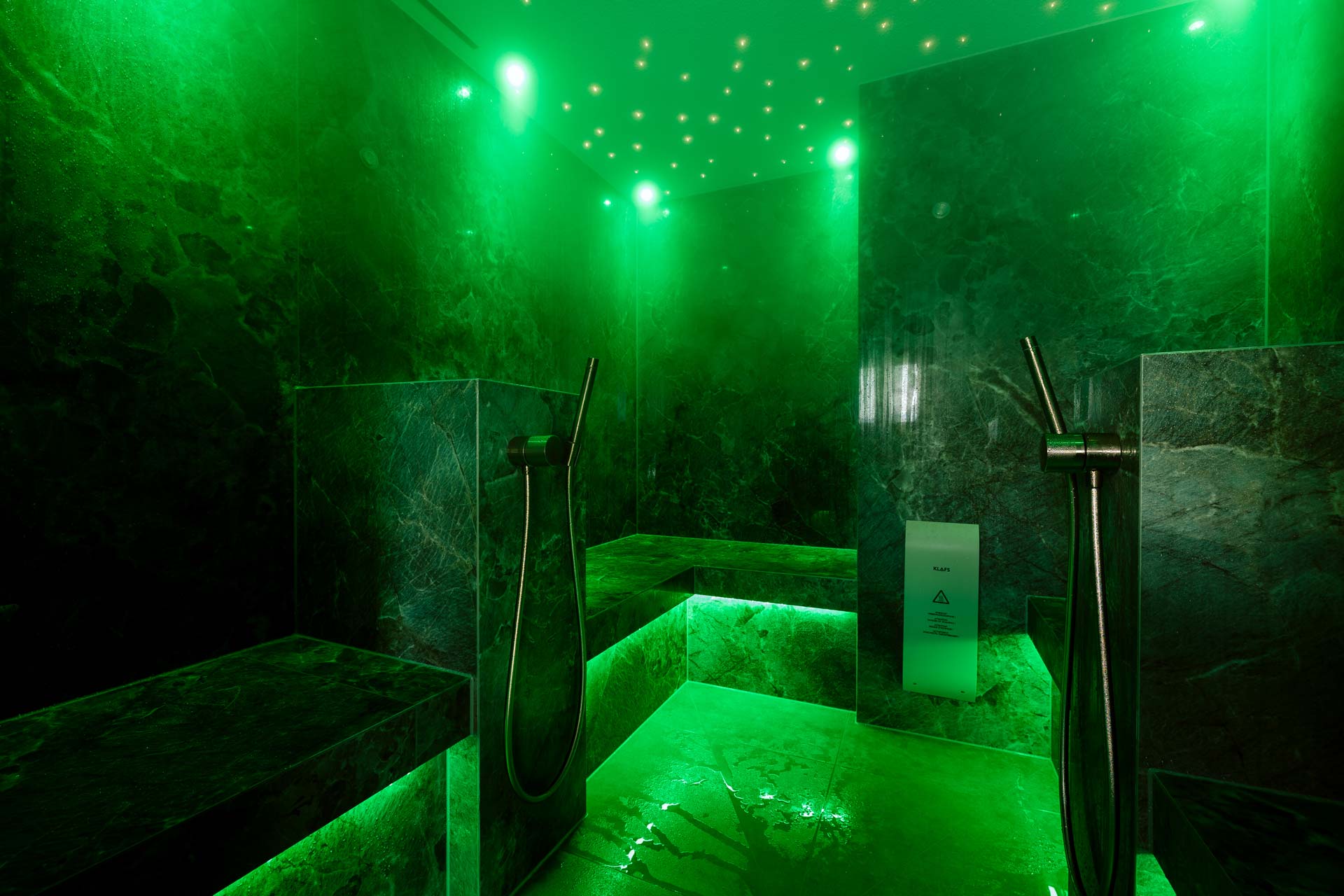 Bright green illuminated marble steam bath with two shower hoses