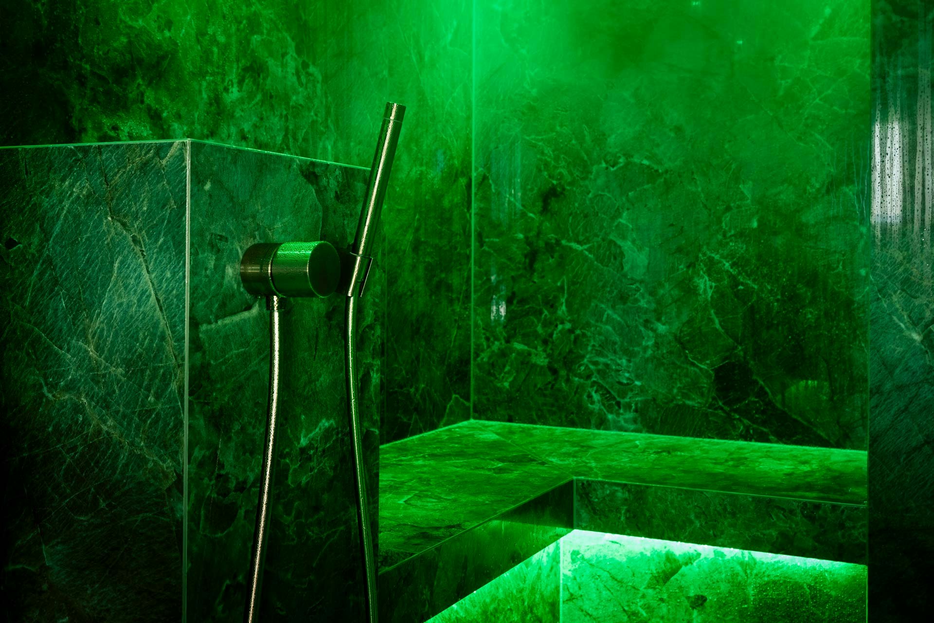 Bright green illuminated marble steam bath with shower hose