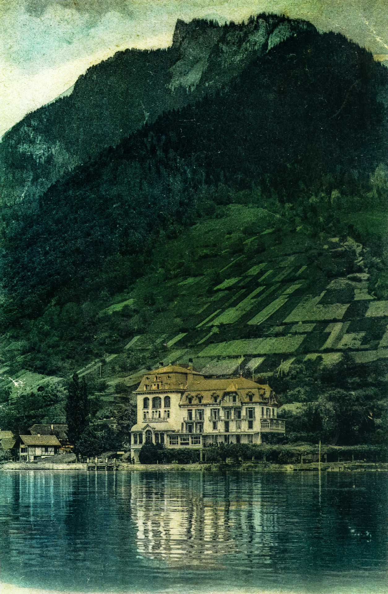 Kolorierte Postkarte mit dem Vorgängerbau des Hotel BEATUS, davor der See, dahinter ganz gross der Berg