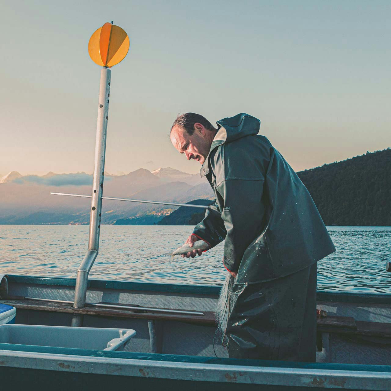 Pêcheur von Gunten sur le lac de Thoune Pêcheur en tenue huilée sur un bateau au bord du lac de Thoune