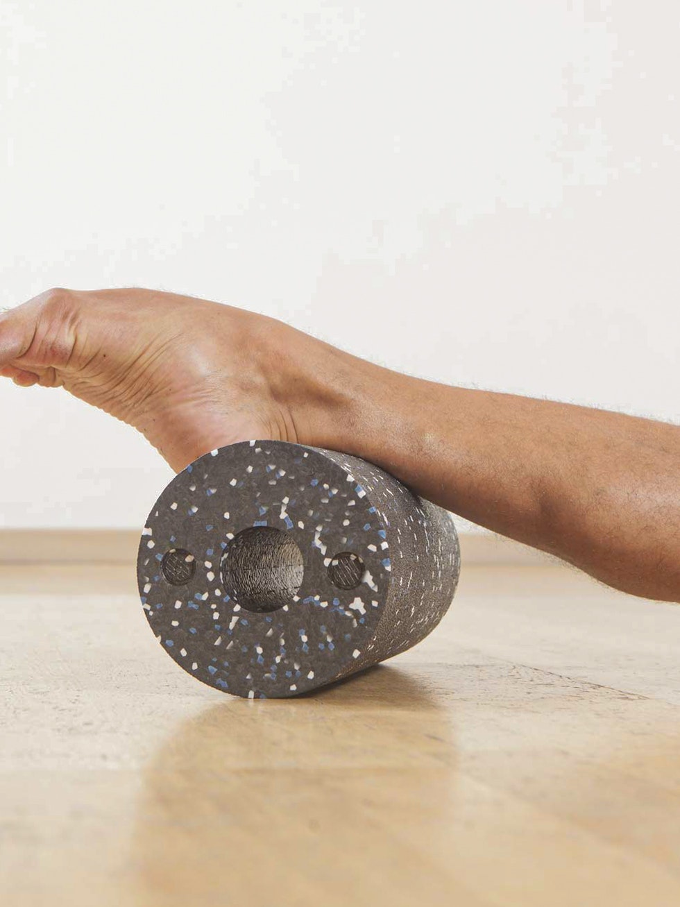 Blackroll Stretched leg and foot on a dark plastic roller