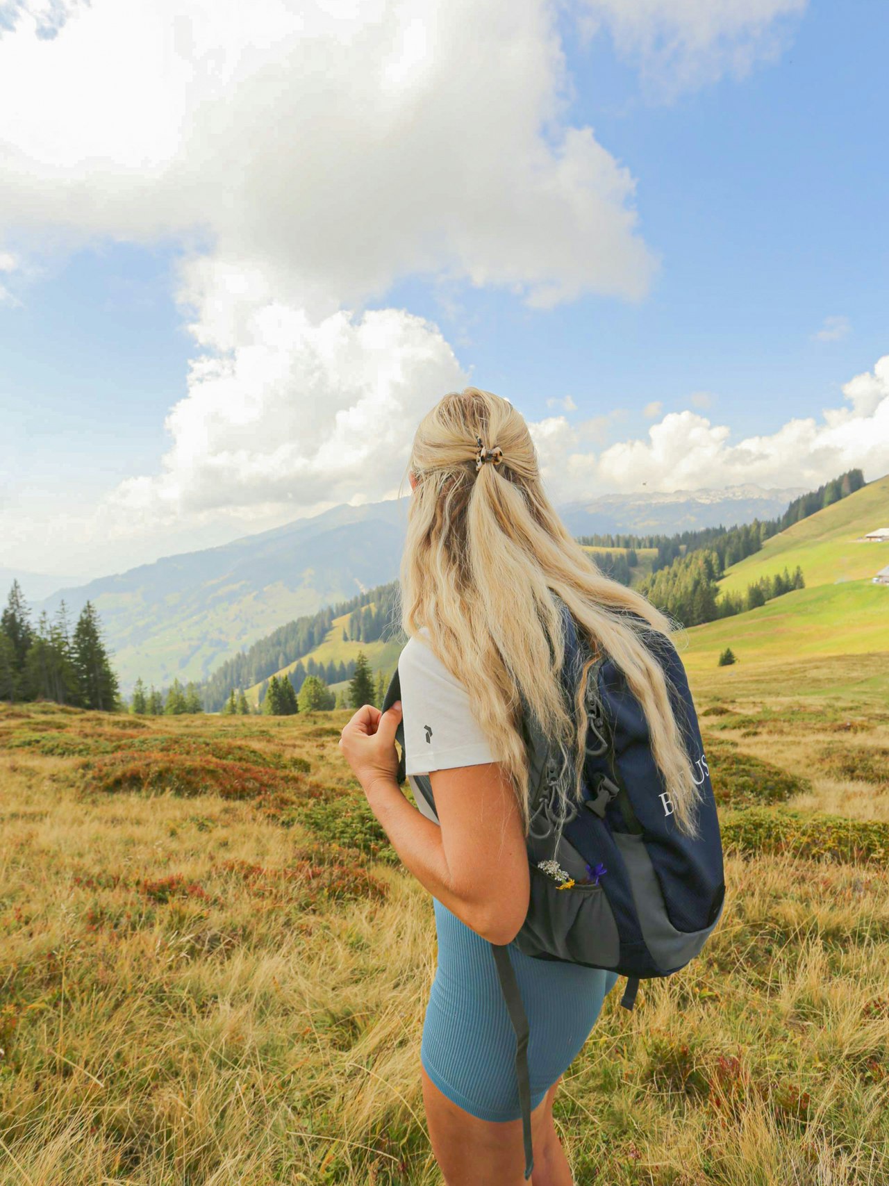 Out and about with the nature guides A woman with a rucksack and shorts looks out over the valley from a mountain meadow